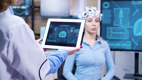 Middle Age Female Doctor Holding Tablet with Patient Brain Activity