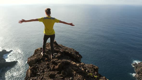 Young Woman Raising Her Arms on Beautiful Steep Cliff Over the Ocean