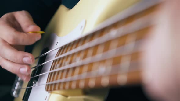 Delighted Bassist Plays White Guitar with Yellow Pick