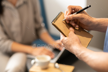 Young waiter going to write down order of client on blank page of notepad