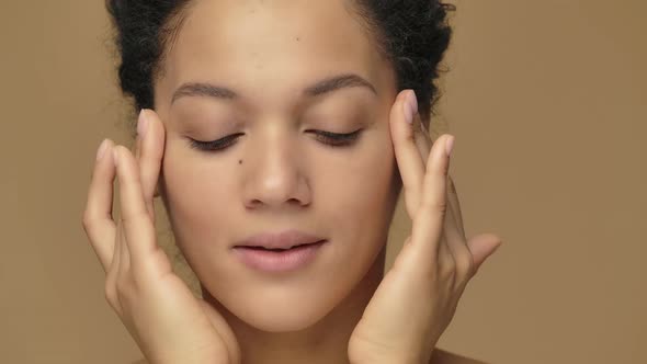 Beauty Portrait of Young African American Woman Striking Face with Fingers and Giving Gentle Skin