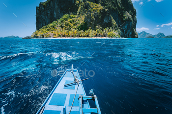  in front of circular Pinagbuyatan Island with huge limestone cliffs and overgrown with coconut palm trees. El Nido, Palawan, Philippines.