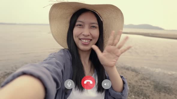 Attractive an Asian female taking a selfie video chat with her friends.