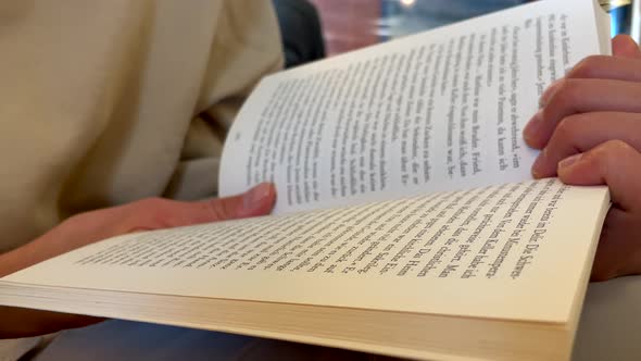 Close up shot of female person holding book and reading indoors in traditional library