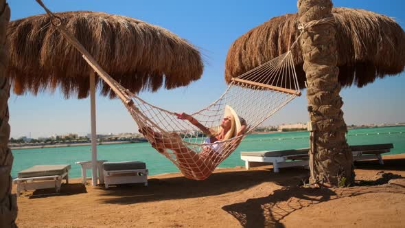 Travel and vacation concept - Woman relaxing on hammock on the beach