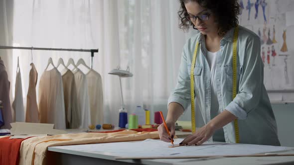 Professional seamstress marking patterns, considering dimensions of customer