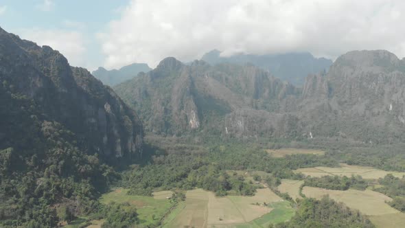 Aerial: flying over scenic cliffs rock pinnacles tropical jungle rice paddies