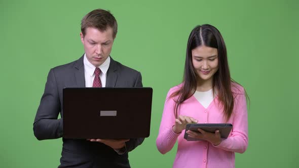 Young Asian Woman and Young Businessman Using Laptop and Digital Tablet Together