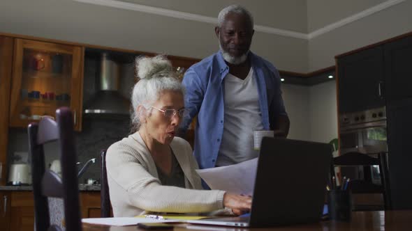 Mixed race senior couple using laptop discussing and calculating finances at home