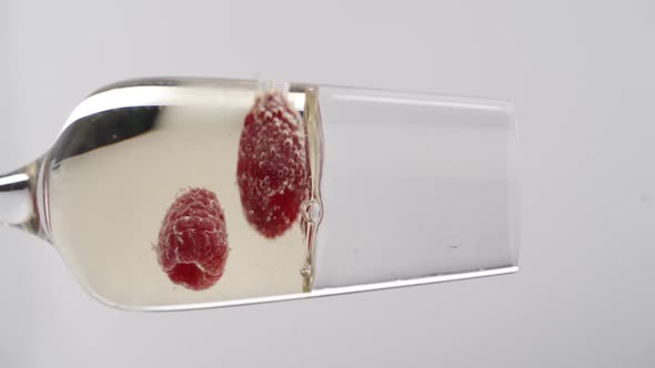 Vertical video, Close-up: strawberries fall into a glass of champagne