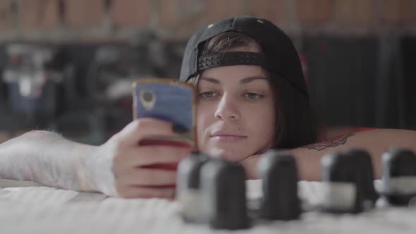 Portrait of Tattooed Hipster Girl Typing a Message in the Smartphone 