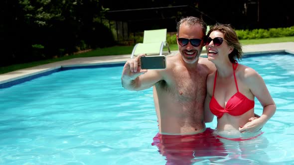 Couple taking a selfie on mobile phone in swimming pool