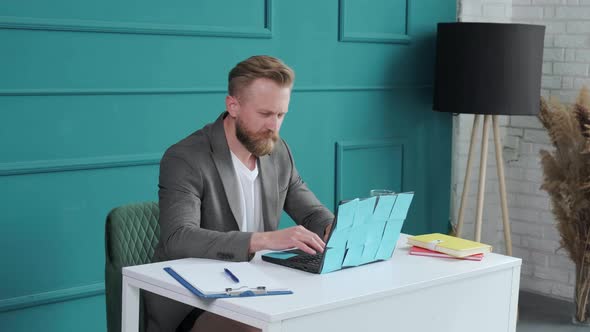 Bearded Man Comfortable at His Desk in Underwear and Jacket Typing at the Computer