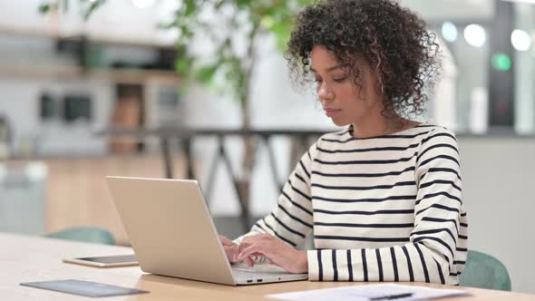 Attractive African Woman with Laptop Looking at Camera in Office