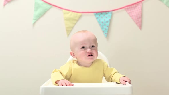 Baby boy sitting in highchair with bunting