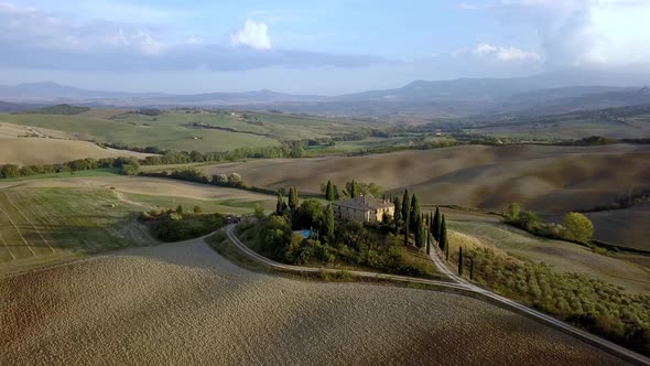 Italian villa on top of a hill with olive trees in the Tuscan countryside, Aerial fly out shot