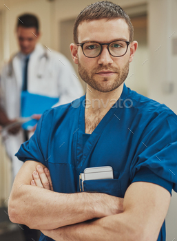 d surgical scrubs standing in a hospital with folded arms looking intently at the camera