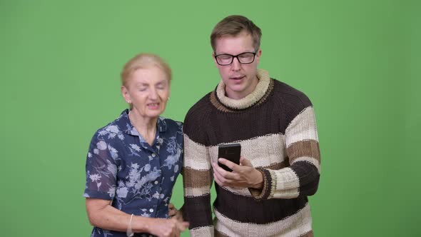 Grandmother and Grandson Using Phone Then Getting Bad News Together