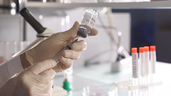 Microbiologist Hands Taking Vaccine From Bottle with the Use of Syringe