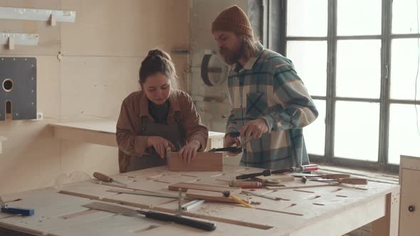Professional Joiner Teaching Young Woman during Carpentry Course