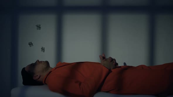 Caucasian Prisoner Lying and Thinking on Plank-Bed in Cell Serving Life Sentence