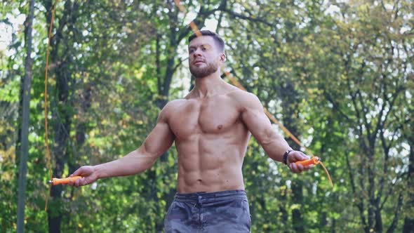 Young man jumping rope outdoor. View of active man doing workout with jumping rope at stadium