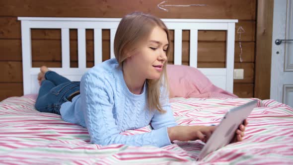 Attractive Smiling Woman Enjoying Break Lying on Bed Using Tablet Full Shot