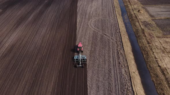 Tractor plows ground on cultivated farm field