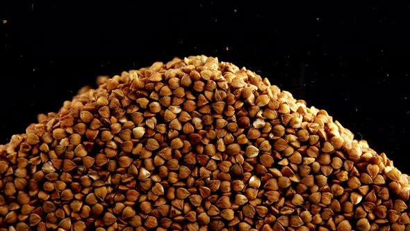 Buckwheat groats are poured on a black background.