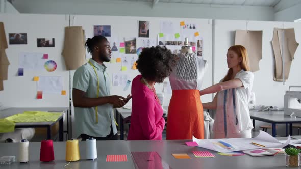 Three colleagues dressing up a model in fashion office