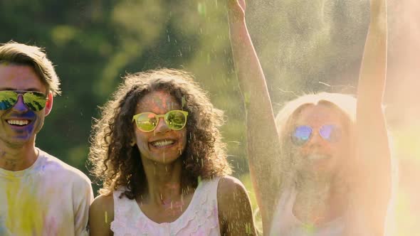 Two Couples in Sunglasses Playfully Throwing Powder Paint at Each Other, Slow-Mo