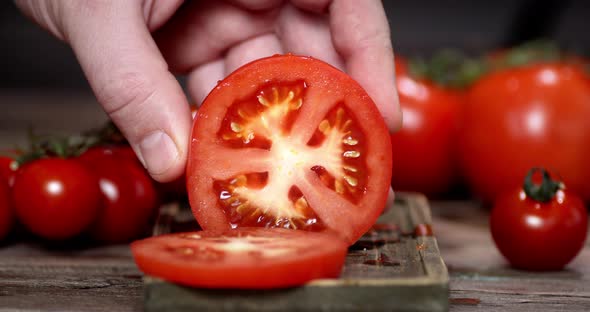 Hand of a Man with a Knife Cut a Fresh Tomato Into Pieces