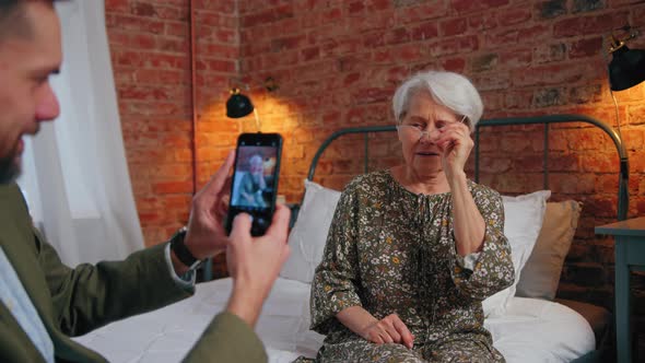 Grinning Content Elderly Pensioner Mother Posing for a Photo Taken By Her Middleaged Son Mother's