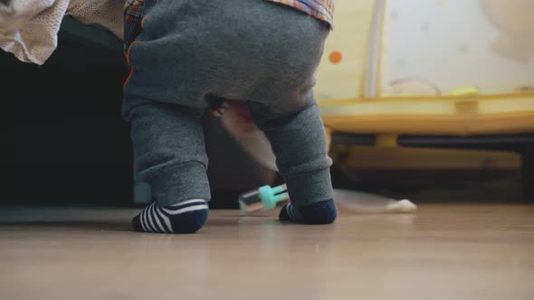 Playful Baby Plays with Nozzle Suction at Large Bed on Floor