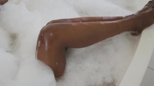 Legs of african american attractive woman relaxing in foam bath in bathroom