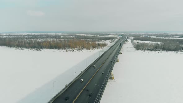 Cars Drive Along Gray Bridge Making Shadow on Frozen River