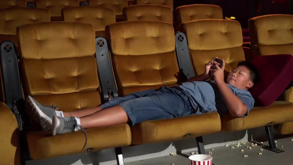 A Boy Laying Down and Playing Mobile Phone