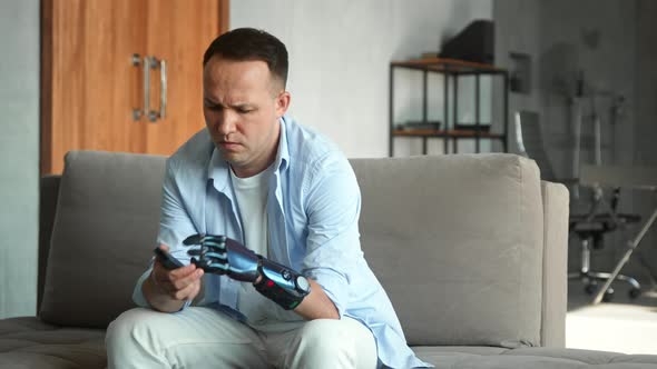 Serious man with artificial bio hand prothesis checks batteries in television