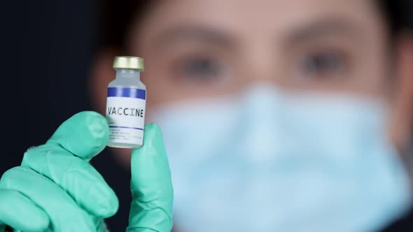 Medical professional holding up vaccine vial looking at camera