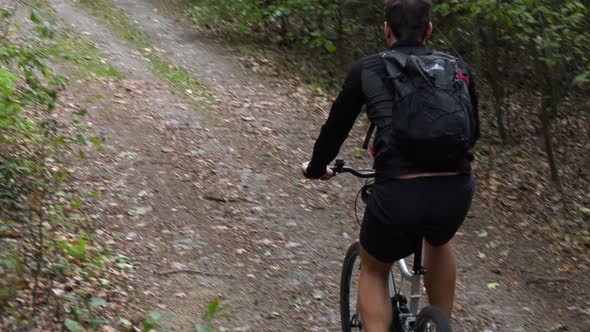 A Cyclist Rides Down a Path Through a Rural Area - Top Rear View