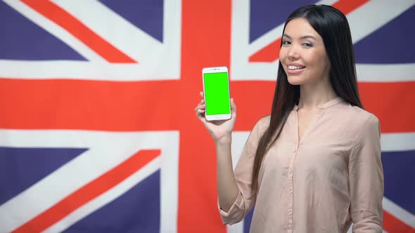 Lady Showing Phone With Green Screen Against British Flag on Background, App