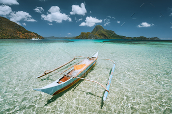 nca boat in front of Cadlao Island in crystal clear shallow water during low tide.