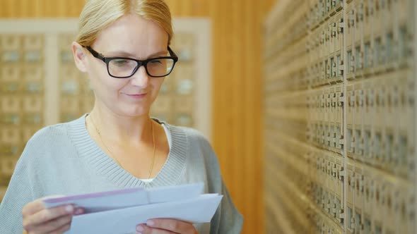 Portrait of a Young Stylish Woman with a Bundle of Letters in Her Hands in the Post Office