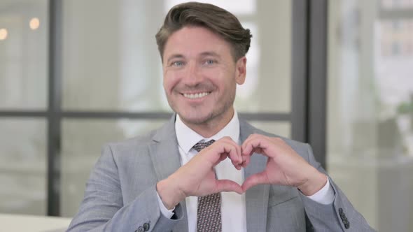 Portrait of Middle Aged Man showing Heart Shape by Hands