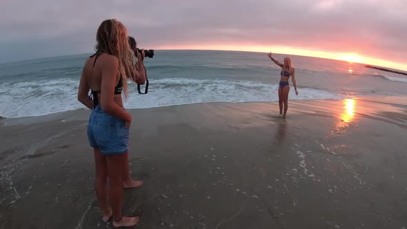Young women taking photos of teen in swimsuit posing on the beach