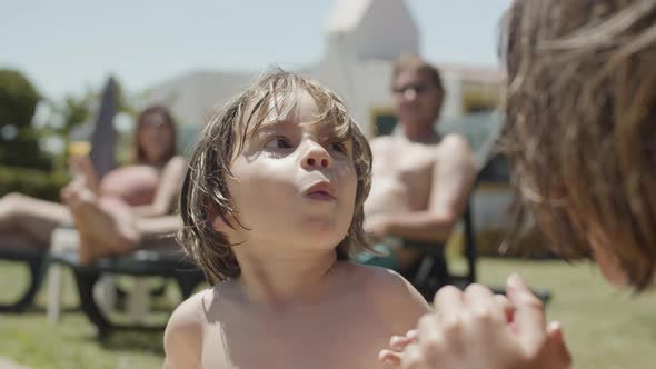 Cute Little Boy Sitting Near Swimming Pool and Eating Candy