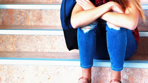 Sad schoolgirl sitting alone on staircase