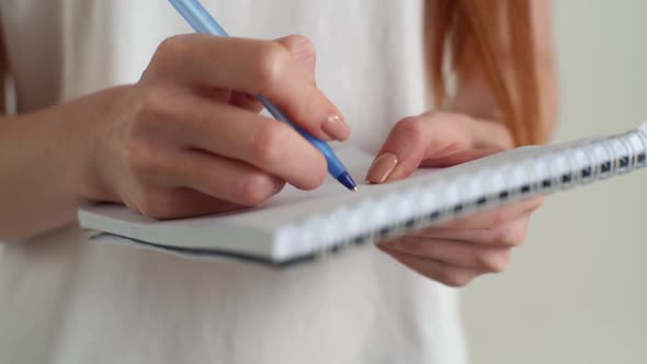 Closeup Hands of Unrecognizable Young Woman Writing Notes in Paper Notebook on White Isolated