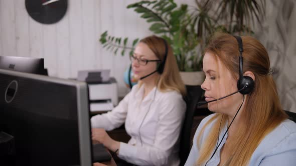 Two Tired Women Take Off Their Headphones in the Office After Work