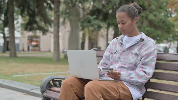 Online Shopping By Excited African Woman While Sitting Outdoor on Bench